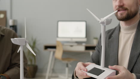 Businessman-Explaining-Wind-Turbine-Model-To-Colleagues-In-The-Office-1