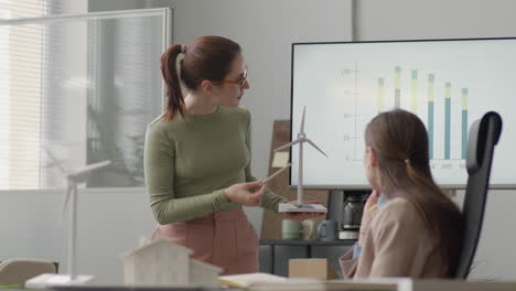 Businesswoman-Explaining-Wind-Turbine-Model-And-Showing-Data-Graph-During-A-Meeting-In-The-Office-2