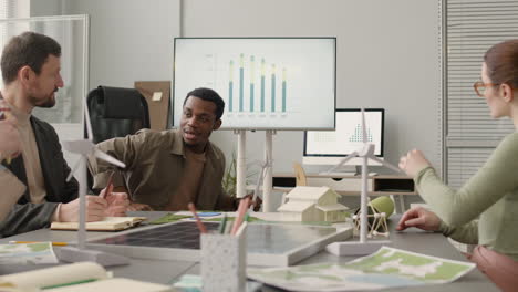 Man-Explaining-Wind-Turbine-Model-And-Showing-Data-Graph-During-A-Meeting-In-The-Office