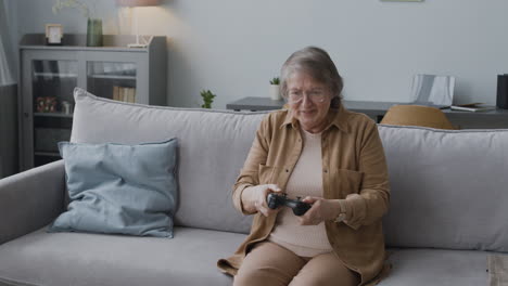 Glückliche-ältere-Frau,-Die-Videospiel-Spielt,-Während-Sie-Zu-Hause-Auf-Dem-Sofa-Sitzt