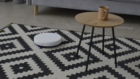 White-Robot-Vacuum-Cleaner-Sucking-Dust-On-A-Carpet-In-A-Modern-Living-Room