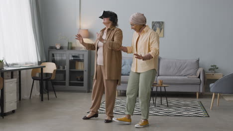 Middle-Aged-Arabic-Woman-Helping-A-Senior-Lady-To-Use-Virtual-Reality-Headset-Glasses-At-Home-2