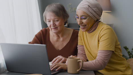 Arabic-Woman-Teaching-An-Elderly-Woman-To-Use-A-Laptop-At-Home-2