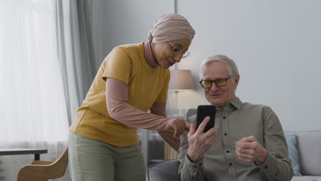 Arabic-Woman-Teaching-An-Elderly-Man-To-Use-A-Smartphone