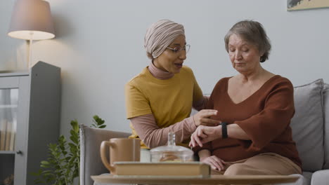 Arabic-Woman-Teaching-An-Elderly-Woman-To-Use-A-Smartwatch