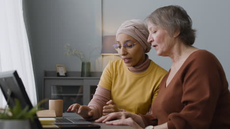 Mujer-árabe-Enseñando-A-Una-Anciana-A-Usar-Una-Laptop