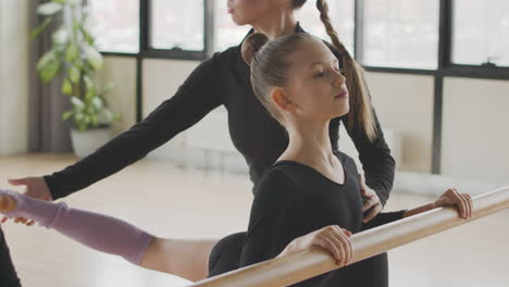 Lehrerin-Korrigiert-Die-Beinposition-Des-Turnmädchens-Im-Ballettunterricht