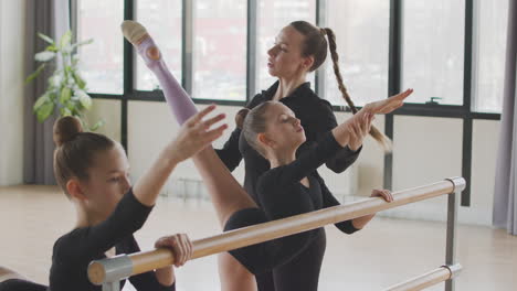 Lehrerin-Korrigiert-Die-Arm--Und-Beinposition-Des-Turnmädchens-Im-Ballettunterricht