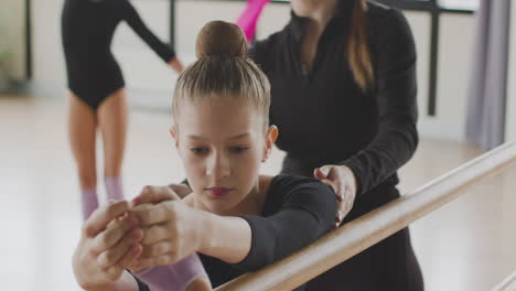 Close-Up-View-Of-A-Gymnastic-Blonde-Girl-Rehearsing-A-Posture-At-The-Ballet-Barre