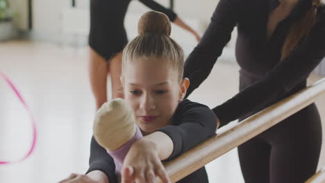 Close-Up-View-Of-A-Gymnastic-Blonde-Girl-Rehearsing-A-Posture-At-The-Ballet-Barre-1