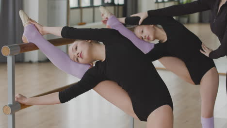 Two-Gymnastic-Blonde-Girls-Rehearsing-A-Ballet-Move-In-Front-Of-Ballet-Barre-4