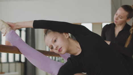 Close-Up-View-Of-Gymnastic-Blonde-Girl-Rehearsing-A-Ballet-Move-In-Front-Of-Ballet-Barre