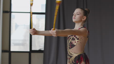 Young-Girl-In-Leotard-Practising-Rhythmic-Gymnastics-With-Clubs-In-A-Studio-5