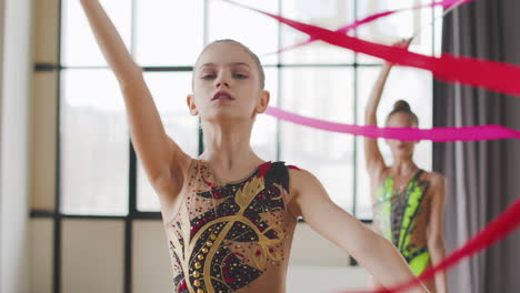 Portrait-Of-Two-Young-Girls-In-Leotard-Practising-Rhythmic-Gymnastics-With-A-Ribbon-During-A-Rehearsal-In-A-Studio