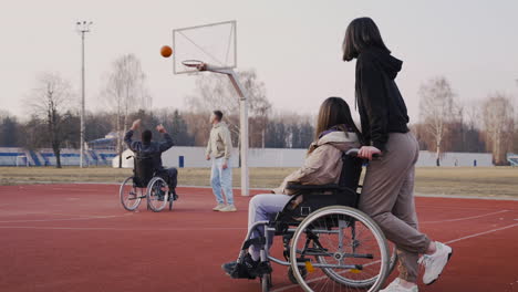 Behinderte-Frau-Im-Rollstuhl-Und-Ihre-Freundin,-Die-Ihren-Freunden-Zusieht,-Wie-Sie-Basketball-Spielen-1