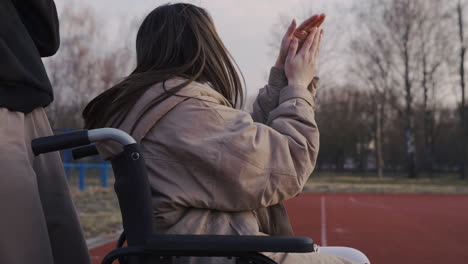 Behinderte-Frau-Im-Rollstuhl-Und-Ihr-Freund-Jubeln-Und-Applaudieren-Seinen-Freunden,-Die-Basketball-Spielen