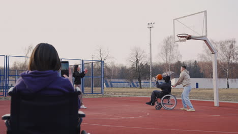 Disabled-Woman-In-Wheelchair-Recording-With-Smartphone-To-Her-Friends-Playing-To-Basketball-2