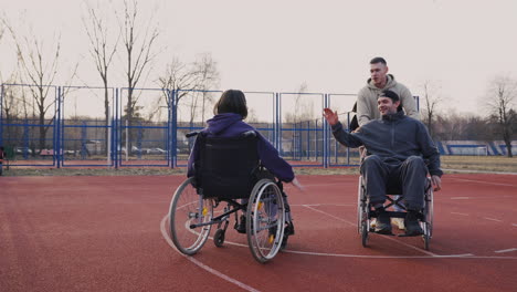 Behinderte-Frau-Im-Rollstuhl-Gibt-Ihren-Freunden-Auf-Dem-Basketballplatz-Ein-High-Five