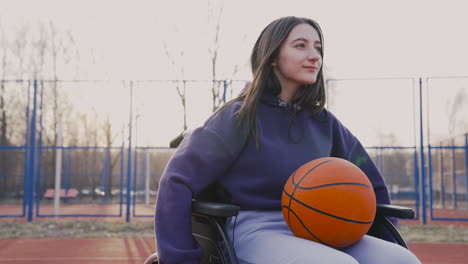 Behinderte-Frau,-Die-Die-Räder-Ihres-Rollstuhls-Auf-Dem-Basketballplatz-Dreht,-Während-Sie-Einen-Basketball-Hält