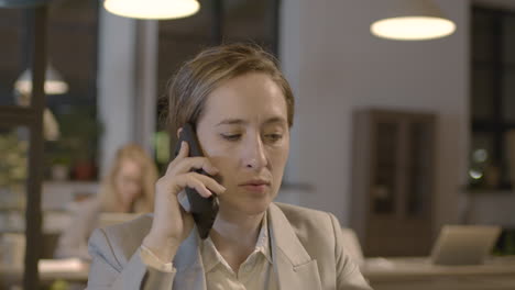Portrait-Of-A-Smiling-Businesswoman-Talking-On-Mobile-Phone-In-The-Office