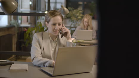 Geschäftsfrau,-Die-Am-Handy-Spricht-Und-Am-Laptop-Im-Büro-Arbeitet