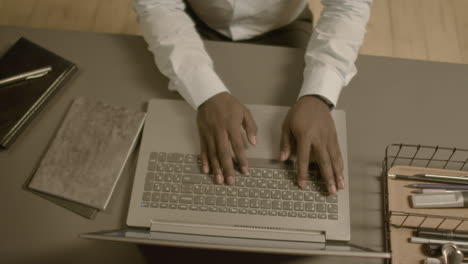 Top-View-Of-Unrecognizable-American-Businessman-Hands-Typing-On-Laptop-Keyboard-At-Workplace