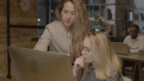 Two-Female-Employees-Looking-Something-At-Computer-And-Talking-Together-In-The-Office-3