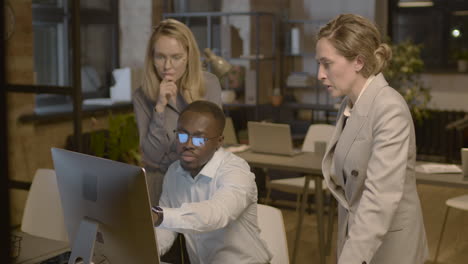 American-Businessman-Showing-Something-On-Computer-To-His-Two-Female-Colleagues-And-Discussing-Together-In-The-Office-1