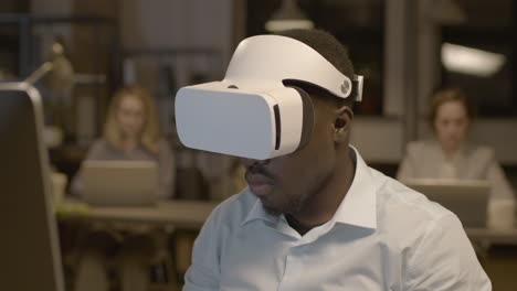 Close-Up-View-Of-American-Man-Sitting-At-Desk-In-The-Office-Wearing-Virtual-Reality-Glasses-2