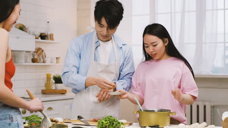 Dos-Mujeres-Y-Un-Hombre-Japoneses-Están-Cocinando-Comida-Japonesa-Mientras-Hablan-Y-Se-Ríen-En-La-Cocina