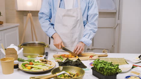 Hombre-Japonés-Cortando-Ingredientes-En-La-Cocina,-Luego-Mira-La-Cámara-Y-Sonríe-1