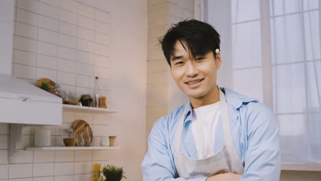 Hombre-Japonés-Cortando-Ingredientes-En-La-Cocina,-Luego-Mira-A-La-Cámara-Y-Sonríe-3