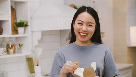 Happy-Japanese-Girl-Eating-Takeaway-Ramen-While-Looking-At-The-Camera-And-Smiling-1