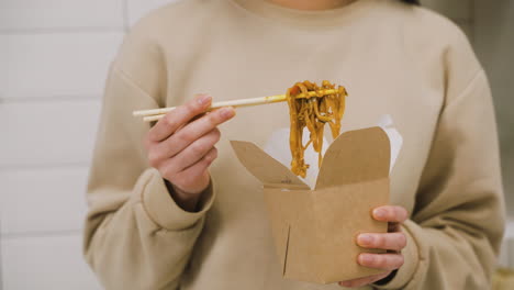 Close-Up-View-Of-A-Woman-Holding-Japanese-Chopsticks-While-Eating-Ramen-In-The-Kitchen