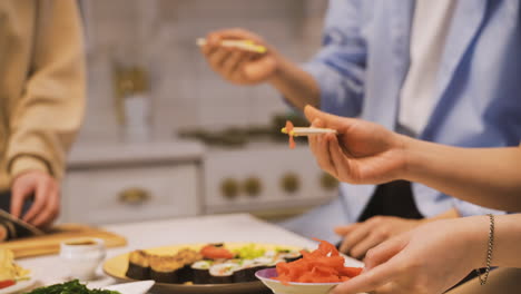 Close-View-Of-A-Plate-Of-Sushi-And-Hands-Holding-Japanese-Chopsticks