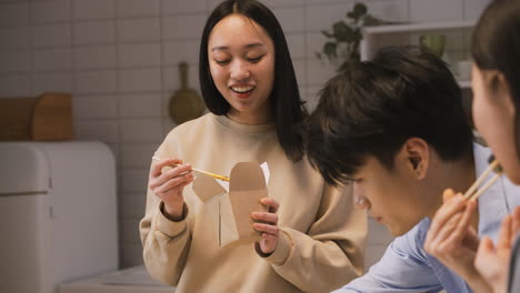 Mujer-Japonesa-Feliz-Sosteniendo-Palillos-Mientras-Come-Ramen-En-La-Cocina