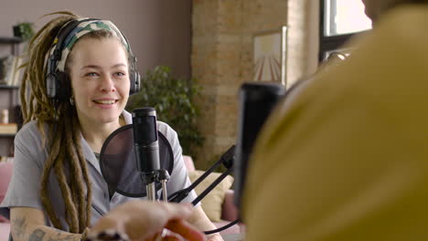Woman-Sitting-At-A-Table-With-Microphones-While-Recording-A-Podcast-With-Man