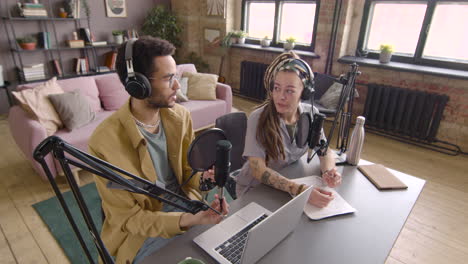 Top-View-Of-Young-Man-And-Woman-Wearing-Headphones-Sitting-At-A-Table-With-Microphones-While-They-Recording-A-Podcast-1