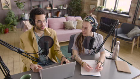 Top-View-Of-Young-Man-And-Woman-Wearing-Headphones-Sitting-At-A-Table-With-Microphones-While-They-Recording-A-Podcast-2