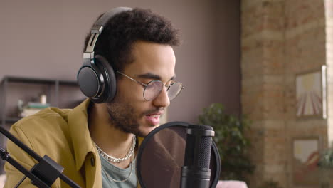 Close-Up-View-Of-Man-Wearing-Glasses-While-He-Is-Talking-Into-A-Microphone-And-Recording-A-Podcast