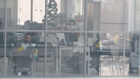 View-From-Outside-Of-And-Arabic-Cleaning-Man-Cleaning-The-Window-Panes-Inside-An-Office-1