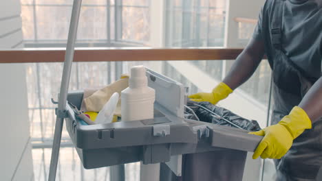 Close-Up-View-Of-Cleaning-Man-Hands-Carrying-Cleaning-Cart-Inside-An-Office-Building