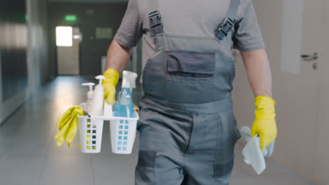 Close-Up-View-Of-Cleaning-Man-Hands-Carrying-Cleaning-Products-While-Walking-Inside-An-Office-Building
