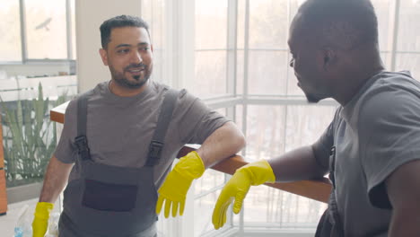 Close-Up-View-Of-And-Arabic-Cleaning-Men-Wearing-Gloves-And-Uniform-Talking-Near-A-Cart-Cleaning