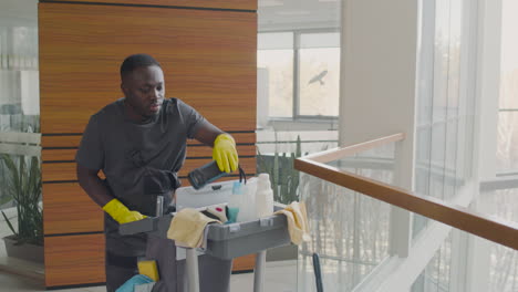 Cleaning-Man-Carrying-A-Cleaning-Cart-Inside-An-Office-Building