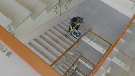 Top-View-Of-Arabic-Cleaning-Man-Wearing-Gloves-Cleaning-Stairs-With-Mop-Inside-An-Office-Building-2