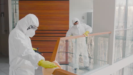 Two-Cleaning-Men-Wearing-Personal-Protective-Equipment-Cleaning-Stair-Railings-Inside-An-Office-Building