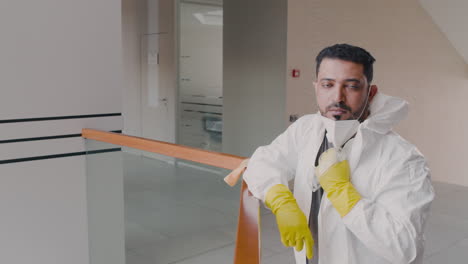 Arabic-Man-Wearing-Personal-Protective-Equipment-Looking-At-Camera-While-Taking-Off-The-Mask-Inside-An-Office-Building