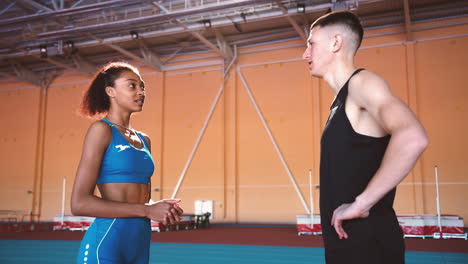 Young-Sportswoman-And-Sportsman-Talking-Together-In-An-Indoor-Sport-Facility-During-Training-Session