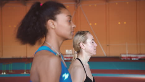 Nahaufnahme-Von-Zwei-Multiethnischen-Sportlerinnen,-Die-Zusammen-Auf-Einer-Indoor-Strecke-Laufen